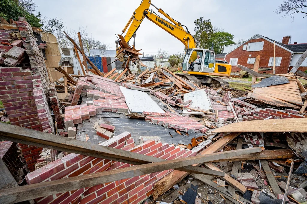 Excavator tearing down an old residential structure