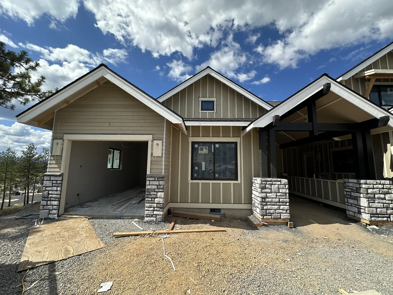 Residential build at framing stage with gable roof structure and stone column entry
