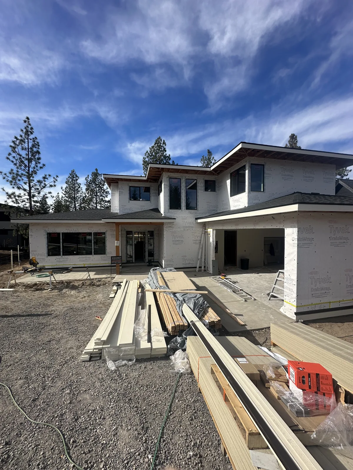 Building corner with wall framing, house wrap and lumber staged on site